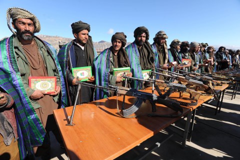 Taliban fighters stand with their weapon