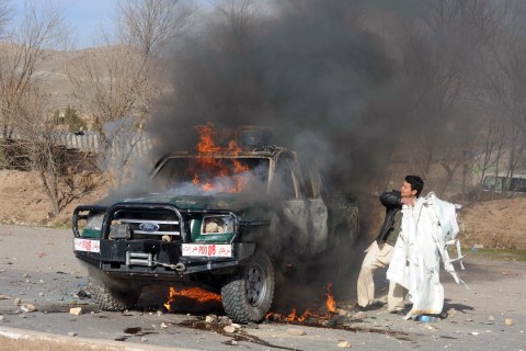 An Afghan demonstrator adds flammable ma
