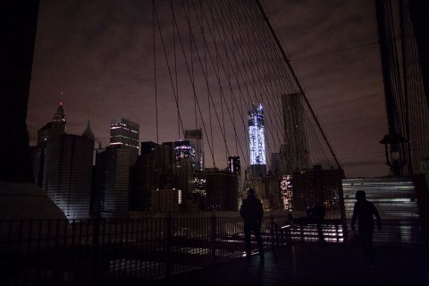 image: Much of lower Manhattan remains dark, as viewed from the darkened Manhattan side of the pedestrian walkway of the Brooklyn Bridge in New York City, Nov. 1, 2012.