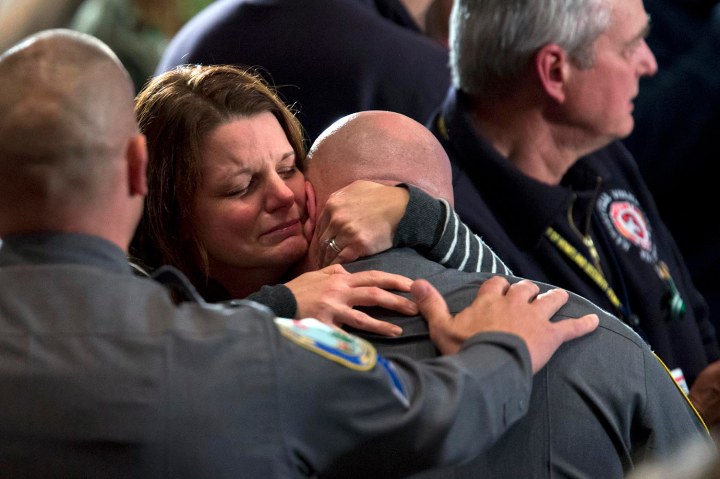 image: A woman hugs a first responder who responded to the mass shooting at Sandy Hook Elementary School during an interfaith vigil at Newtown High School in Newtown, Conn., on Dec. 16, 2012. 