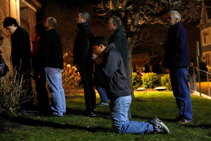 image: People pray and stand outside the overflow area of a vigil at the Saint Rose of Lima church in Newtown, Conn., on Dec. 14, 2012.
