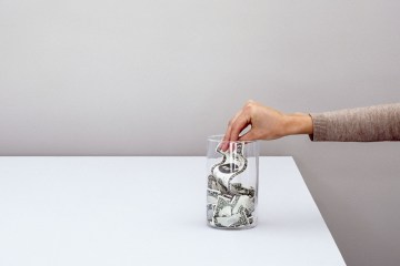 Hand Placing Dollar in Jar