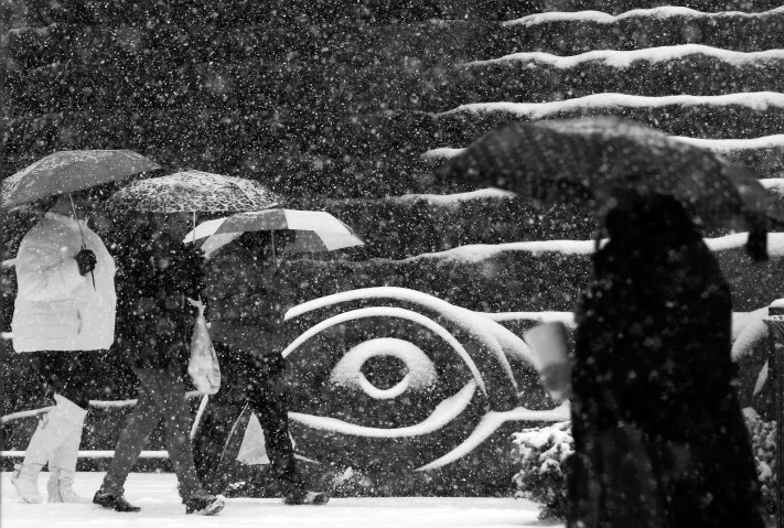 Image: People walk past a downtown Pittsburgh sculpture as snow starts to fall on Dec. 26, 2012. 