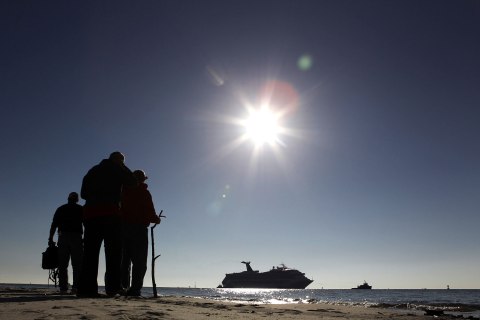 People on Spanish Fort watch as a disabled Carnival Lines cruise ship is towed to harbor off Mobile Bay, Ala., Feb. 14, 2013.