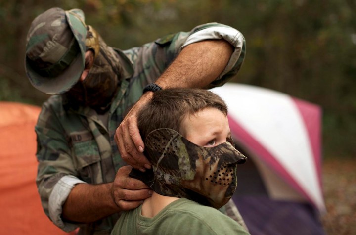 A member of the North Florida Survival Group puts a mask on his son during a field training exercise in Old Town
