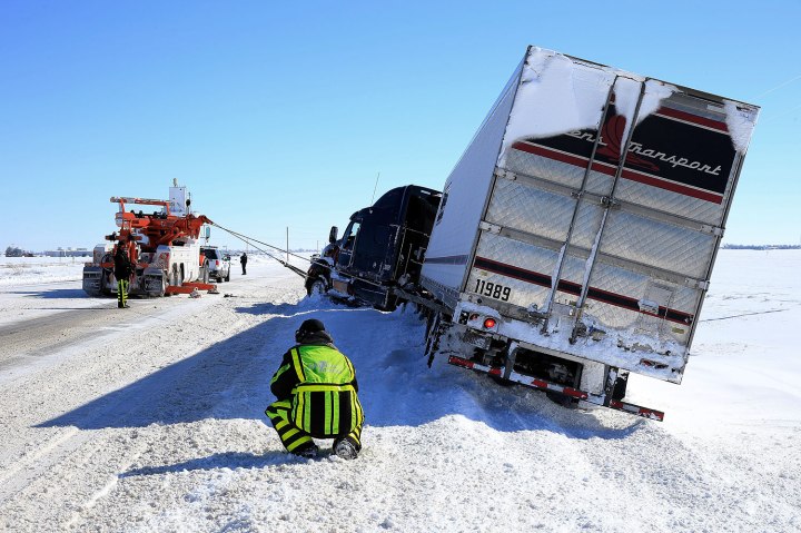 Tow truck drivers extract a semi-truck after it slid off the road in Greensburg, Kan.