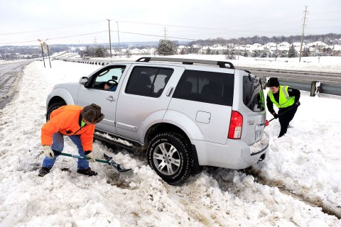City worker Thuan Tran and police officer Christina Batalia help dig out stranded motorist Gary Cook after the area is hit by a snowstorm in Overland Park, Kan