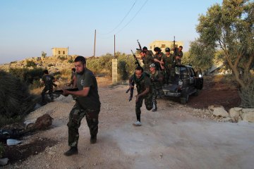 Free Syrian Army members run with their weapons during combat training at Sarmada near Idlib province