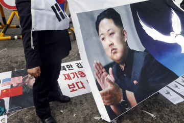 A protester holds a sign showing a portrait of North Korean leader Kim Jong-Un as a portrait of South Korean President Park Geun-hye is seen on the ground during an anti-North Korean protest in Paju