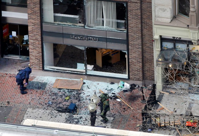 One of the blast sites on Boylston Street near the finish line of the Boston Marathon is investigated by two people in protective suits in the wake of two blasts in Boston Monday.