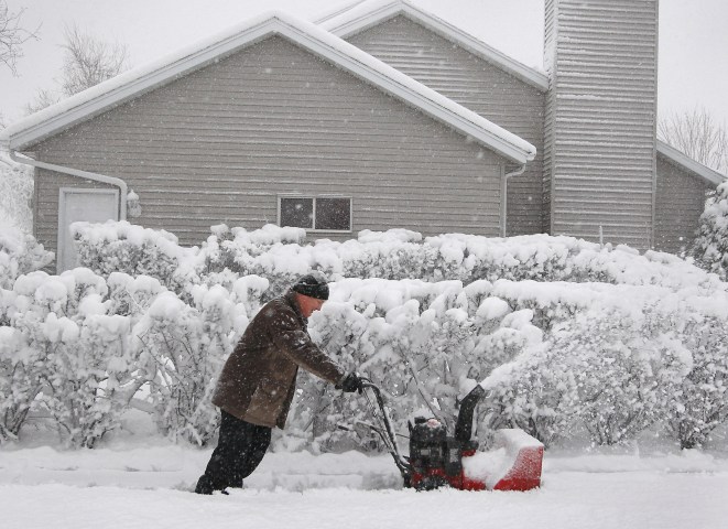 Tarrance Harms pushes on his snow-blower as it struggles to clear the heavy snow off his northeast Rochester, Minn., on May 2, 2013. 