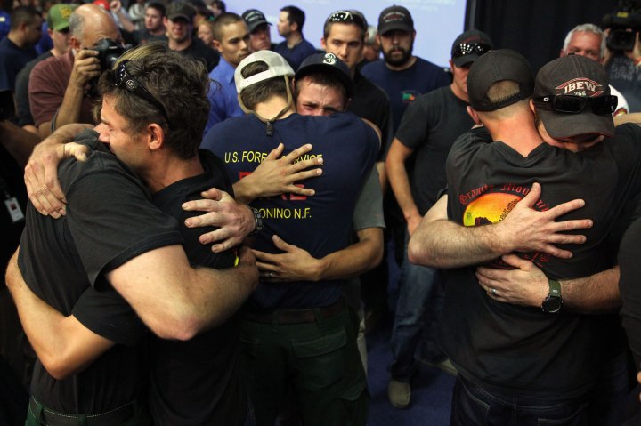 Local firefighters come together and embrace after being honored at a memorial service at EmbryRiddle Aeronautical University in Prescott, Ariz., on July 1, 2013 in Prescott, Arizona.