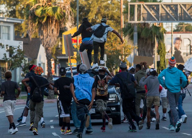 People jump on a car on Crenshaw Boulevard during a protest against the acquittal of George Zimmerman in the Trayvon Martin trial in Los Angeles, July 15, 2013.
