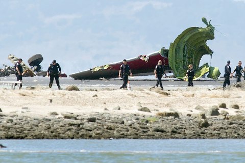 Investigators pass the detached tail and landing gear of Asiana Flight 214 after it crashed at San Francisco International Airport on Saturday, July 6, 2013, in San Francisco.