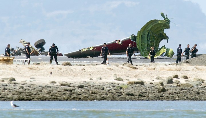 Investigators pass the detached tail and landing gear of Asiana Flight 214 after it crashed at San Francisco International Airport on Saturday, July 6, 2013, in San Francisco.