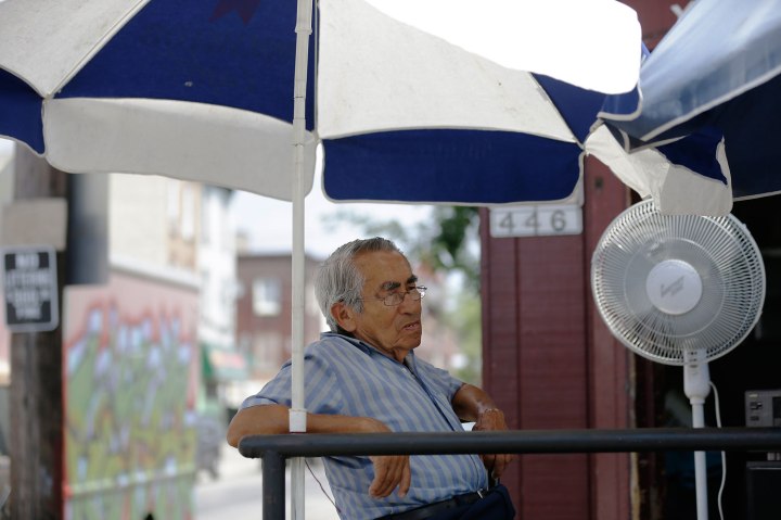 Amalio Medina sits in front of his un-air conditioned shop in the midday heat in Philadelphia, July 18, 2013.