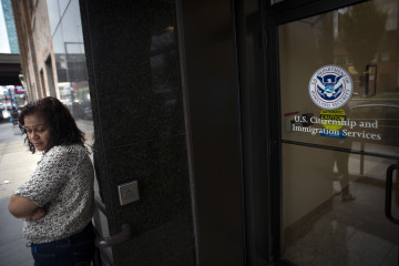 A woman stands on the steps of the U.S. Citizenship and Immigration Services offices in New York
