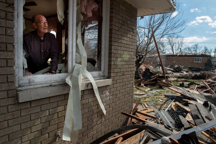 Chuck Phillips looks out at the destruction around him after a tornado tore off part of his roof and left houses around him destroyed in Pekin, Ill. on Nov. 17, 2013.