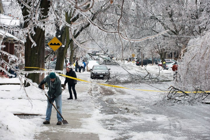 People clear the sidewalks on a closed off street in Toronto after an ice storm knocked down trees and power lines in much of the city, on Dec. 22, 2013.