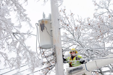 Dave Dora, a lineman from Grand Haven Board of Light and Power, works on connecting fallen wires on Macon Avenue in Lansing, Mich., on Dec. 23, 2013.