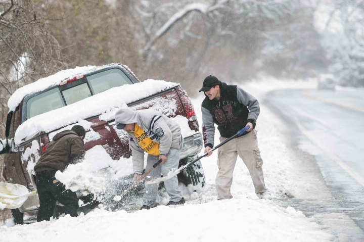 From left: Juan Carlos, Sebastian Guiterrez, and Jose Gutierrez dig out snow around their truck along Lancaster Pike in Wilmington where they spun out of control in the first snow of the season on Dec. 8, 2013.