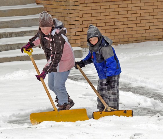 From left: Caitlin Wald, 10, and Jaden Hicks, 7, begin shoveling snow in Mandan, N.D., on Dec. 3, 2013.