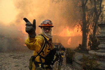 A fireman calls for more water on the burning Singer home above Glendora, Calif., Jan. 16, 2014.