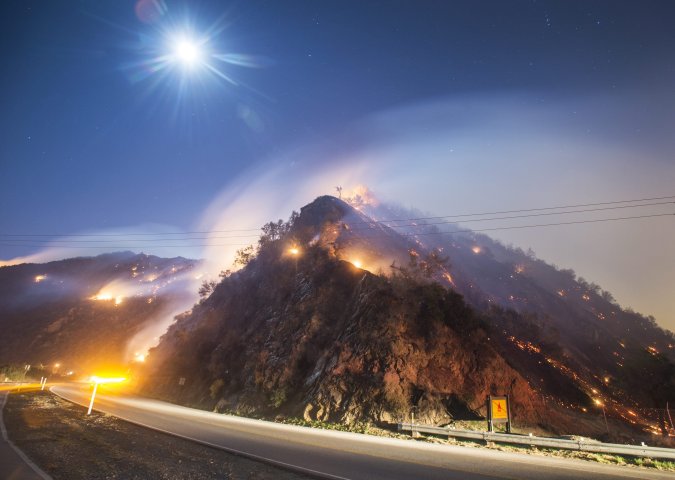 A full moon rises over the active flank of the Colbert Fire off San Gabriel Canyon Road in Azusa, Calif., January 16, 2014.