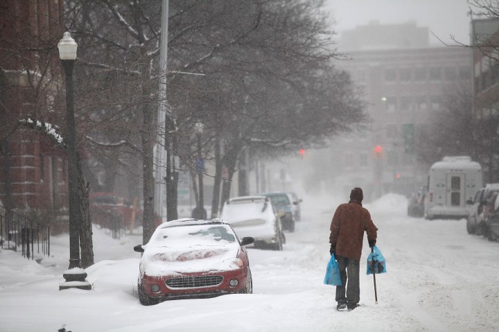 A man uses his cane to navigate a snow covered road in Detroit
